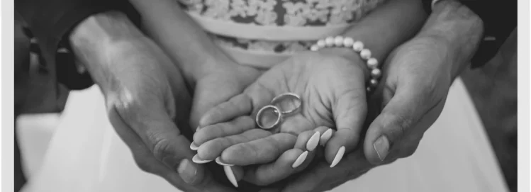 bride and groom holding hands together with wedding rings resting in her palm